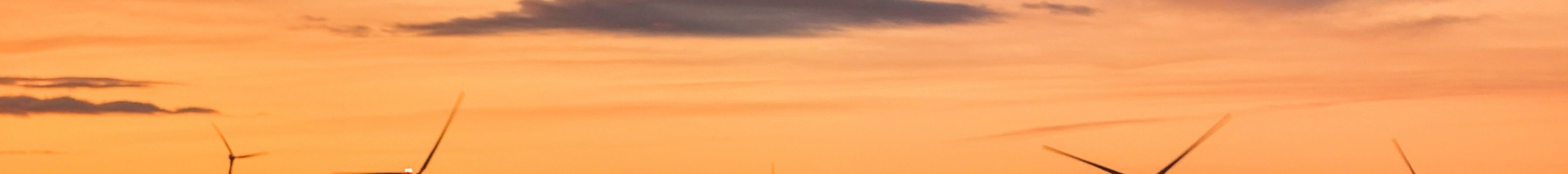 Wind turbines on wind farm under beautiful orange sunset sky at Galway, Ireland, green energy, envir